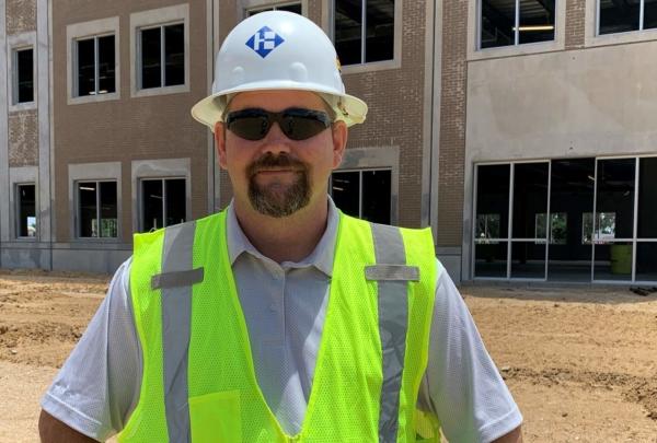 澳门足彩app's Superintendent Sonny Carter posing on a job site wearing a hard hat and safety vest.